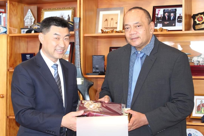 A Tongan man shaking hands with a man of Chinese ethnicity 