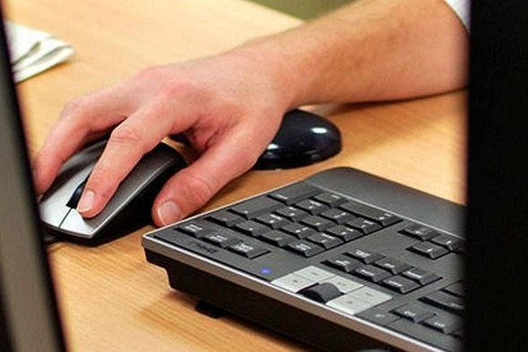 Close up of a hand on a mouse next to a black keyboard