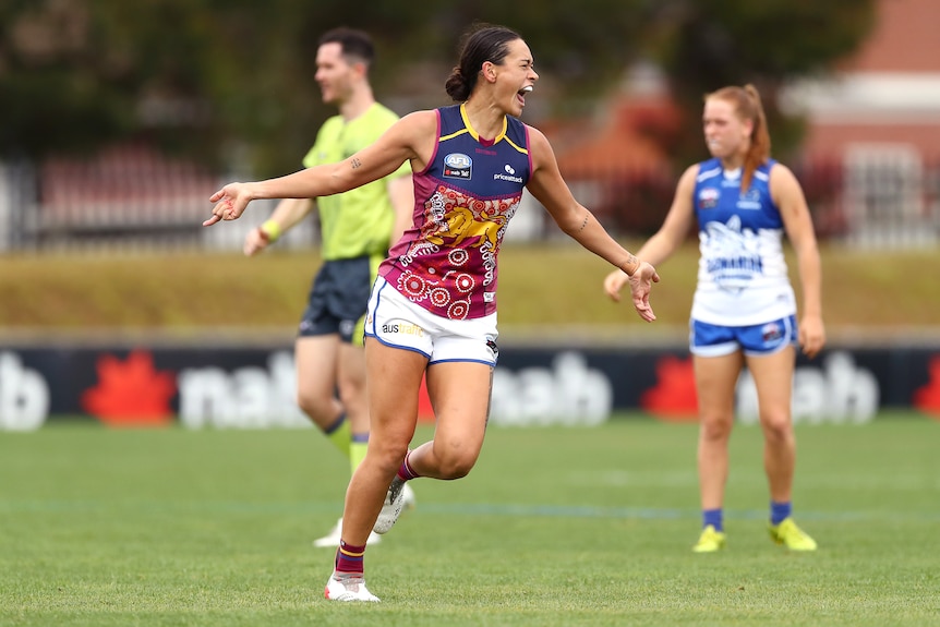 A Brisbane Lions AFLW player celebrates kicking a goal against the Kangaroos.