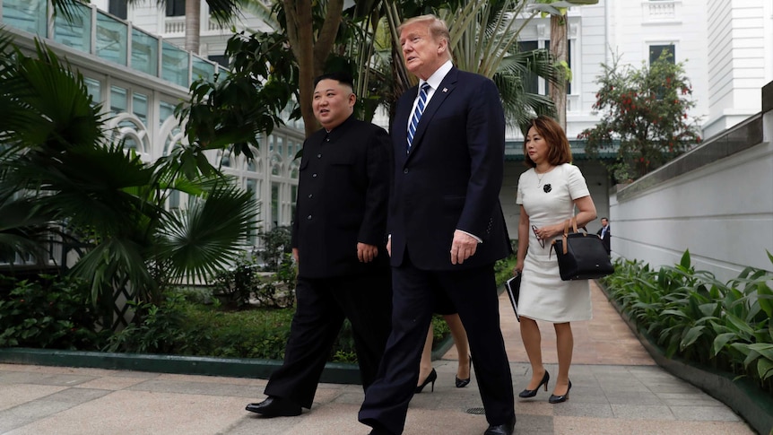President Donald Trump and North Korean leader Kim Jong-un walk in the courtyard outside a hotel.