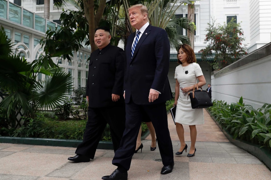 President Donald Trump and North Korean leader Kim Jong-un walk in the courtyard outside a hotel.