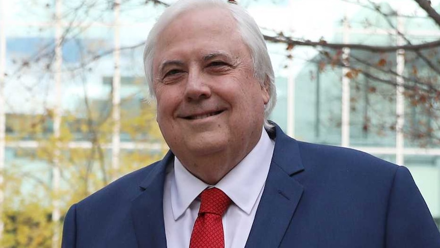 Brian Burston, in a black suit and patterned tie strolls next to Clive Palmer, in a red tie and blue suit.