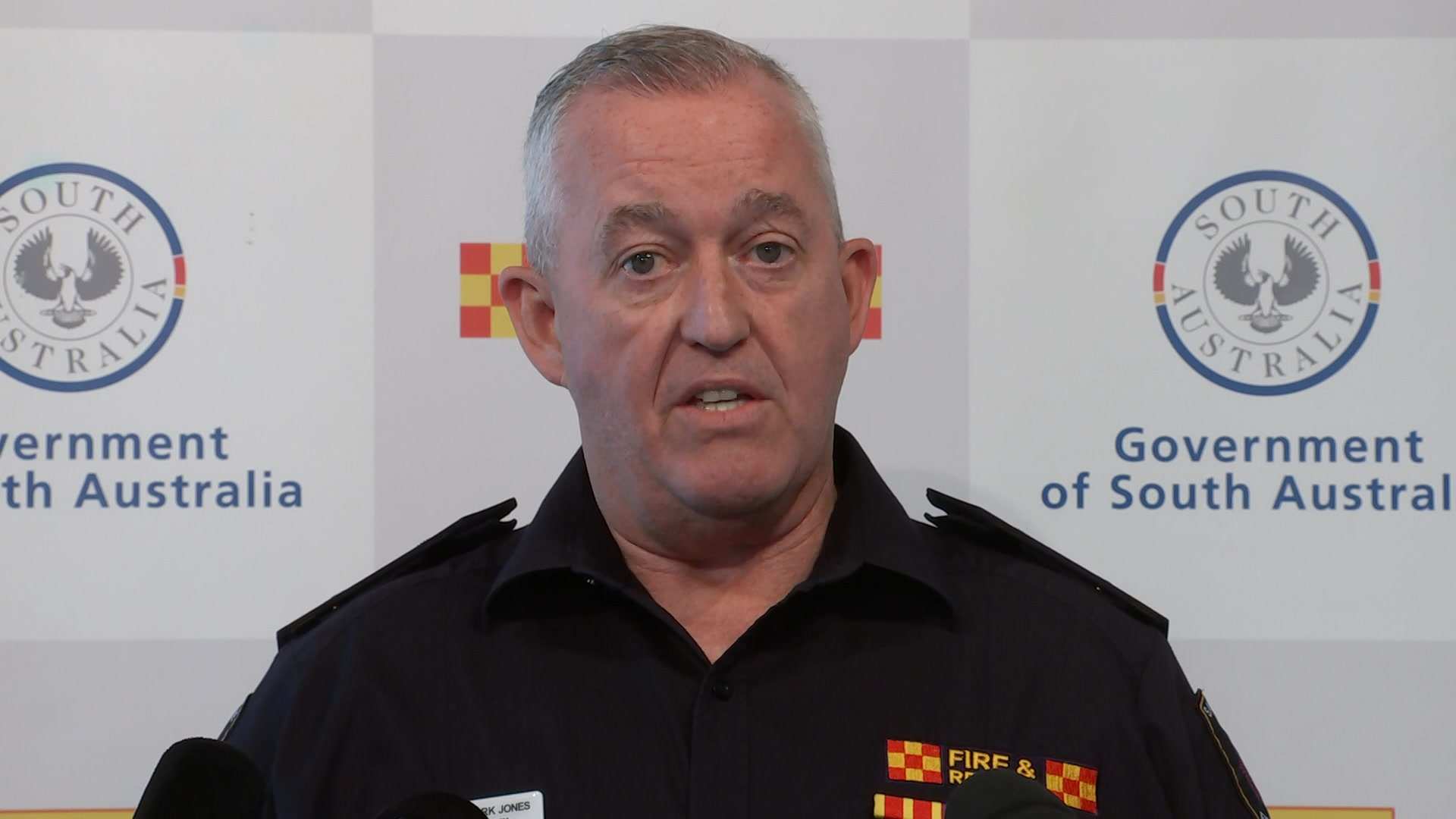 A man wearing a Country Fire Service uniform addresses the media in front of a CFS and Government of South Australia banner.