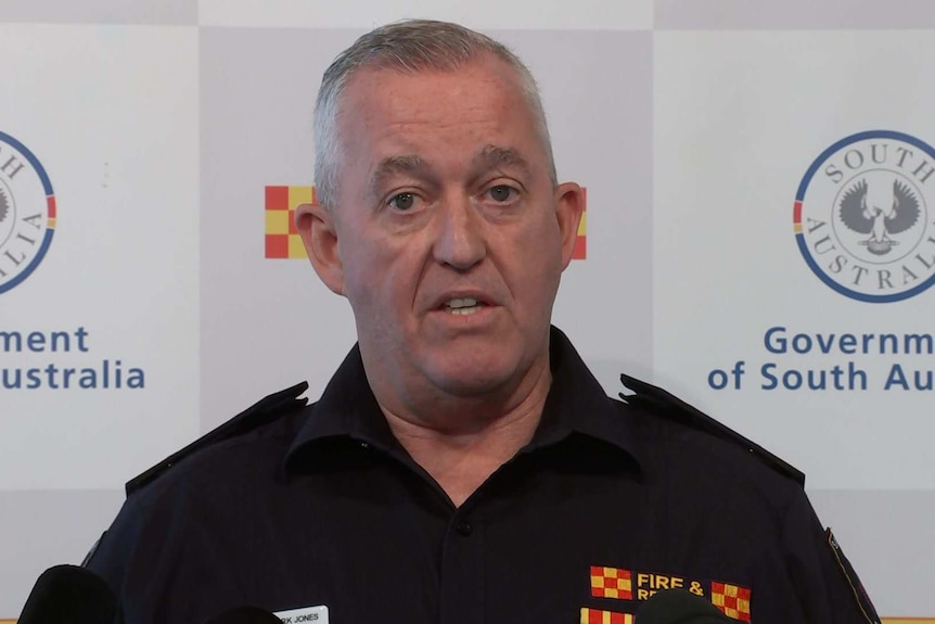 A man wearing a Country Fire Service uniform addresses the media in front of a CFS and Government of South Australia banner.