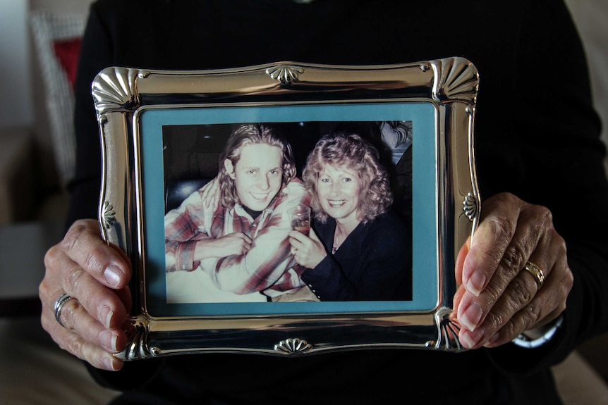 Sally Wilkinson holding a photo frame with a shot of her and her son Daniel.