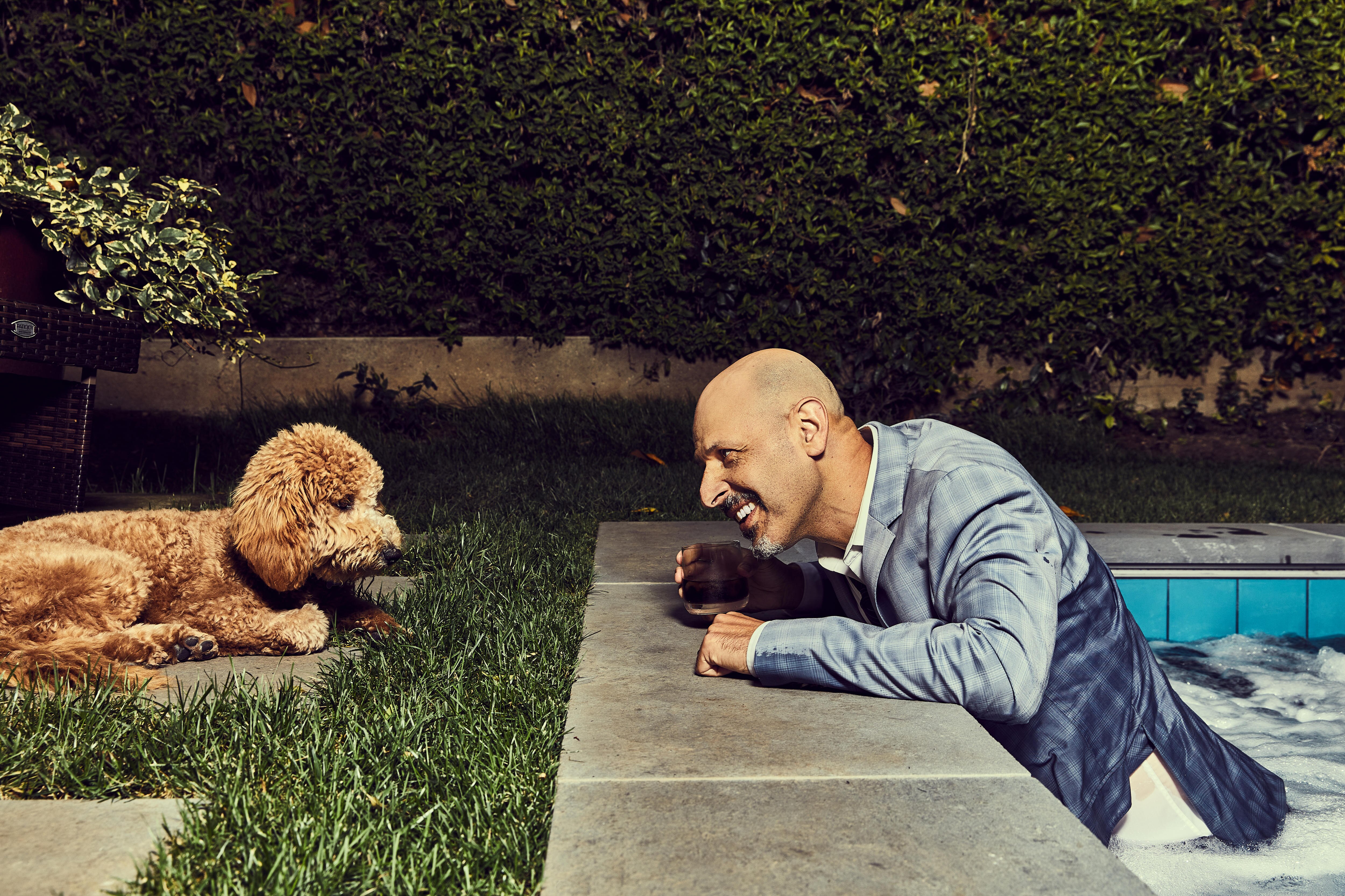 Man in pool staring at dog