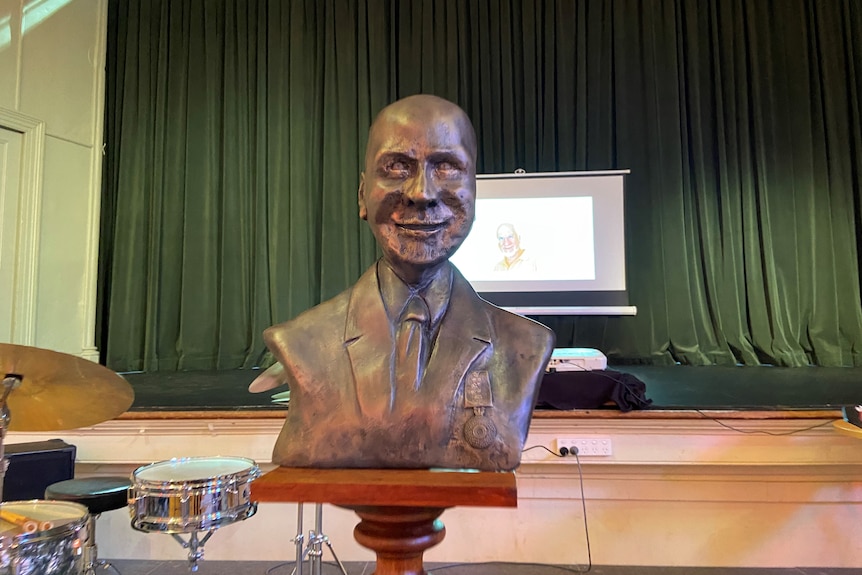 A photo of a bronze statue of a man, on a stage