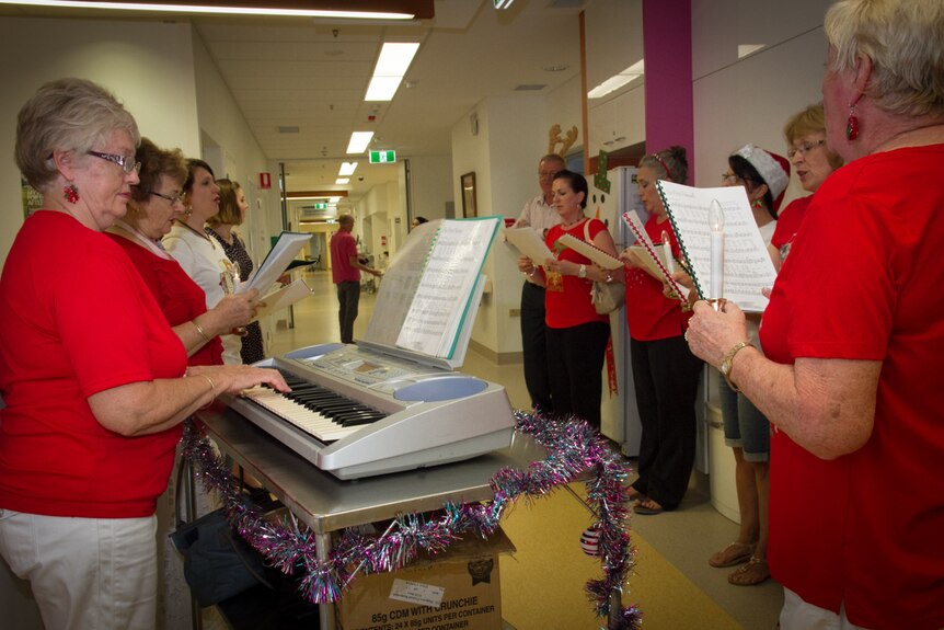 A group of carollers sing in a hospital ward.