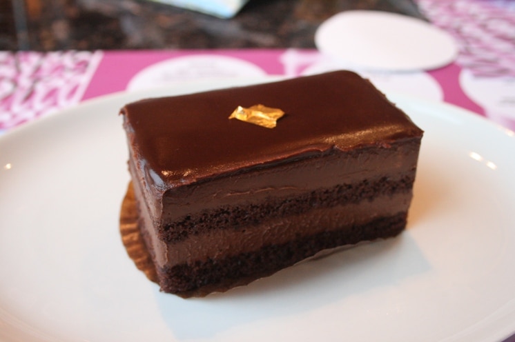 A piece of chocolate cake with a small piece of gold leaf on top.
