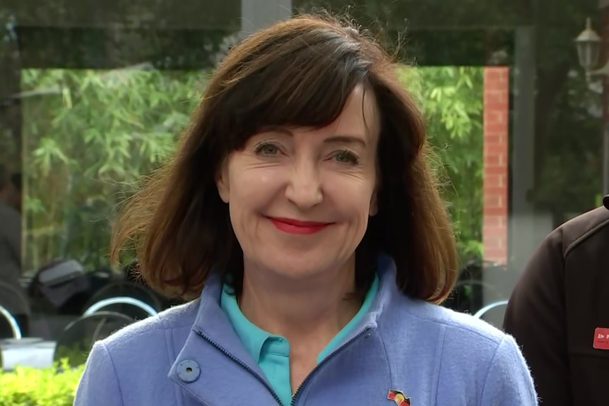 A woman with brown hair wearing a blue jacket