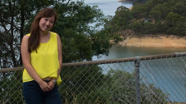 Christina Zhou stands in front of a reservoir.