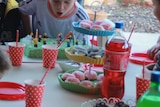 A table laid out for a child's party with a child in the background