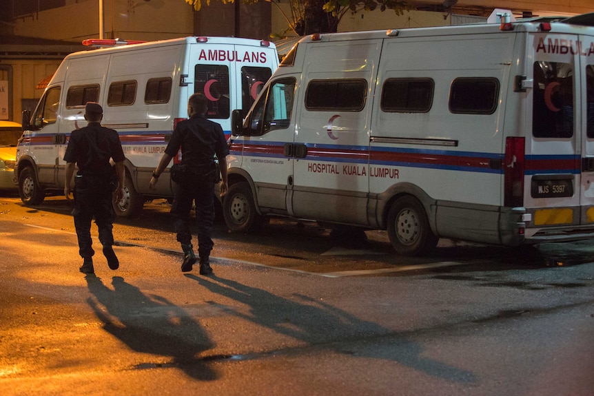 Police walk past ambulances while on patrol at Kuala Lumpur's morgue.