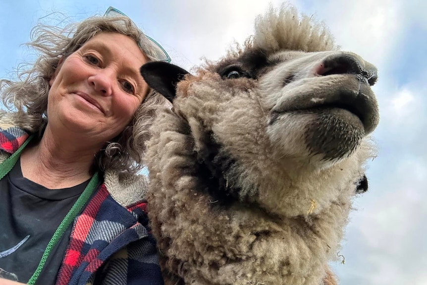 Emma Haswell poses for a photo next to a sheep.