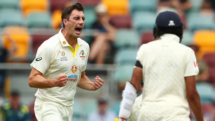 An Australian bowler pumps his fist as he runs near an England batter in the first men's Ashes Test at the Gabba.