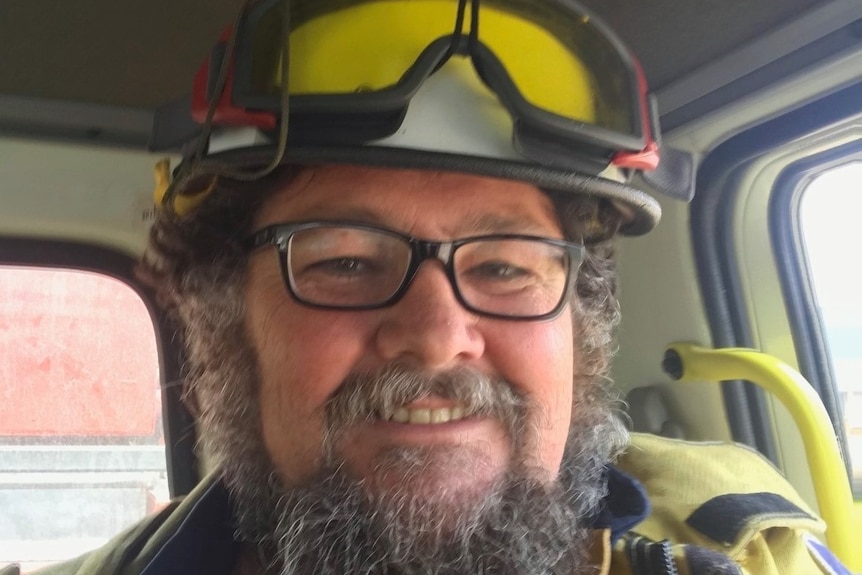 Close up of man with fire fighting helmet and jacket in cabin of fire truck.