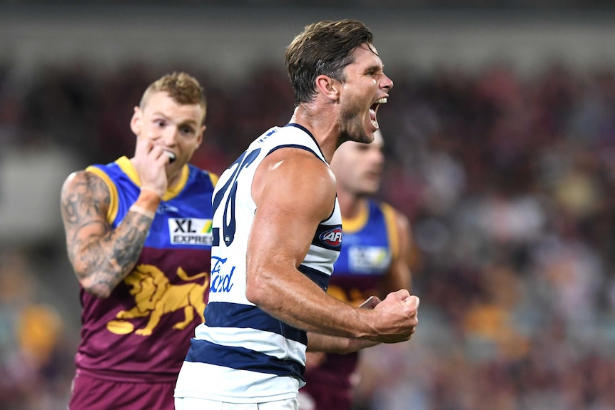 Geelong's Tom Hawkins shouts in celebration in front of Brisbane's Mitch Robinson.