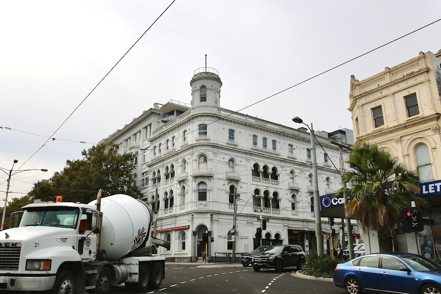 Cars drive past the historic George Hotel in St Kilda on a cloudy day.