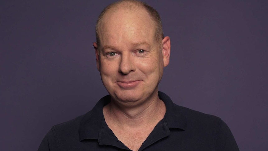 Tom Gleeson smiles at the camera in a still from an ABC Life video.