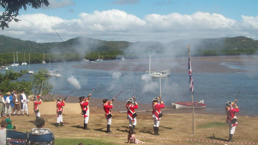 A crowd watches men in period costume fire muskets into the air at the Cooktown Discovery Festival.