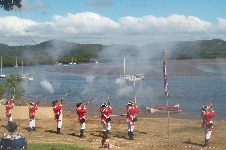 A crowd watches men in period costume fire muskets into the air at the Cooktown Discovery Festival.