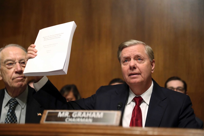 Senator Lindsey Graham holds up a report in one hand