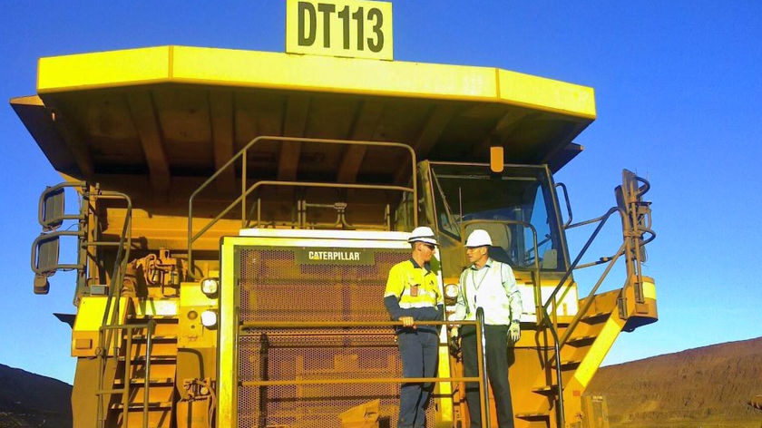 Tony Abbott on the front of a giant yellow mining truck at FMG's, Fortescue Metals Group, Cloudbreak mine in the Pilbara