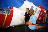Investigators walk near a section of the tail of AirAsia Flight QZ8501