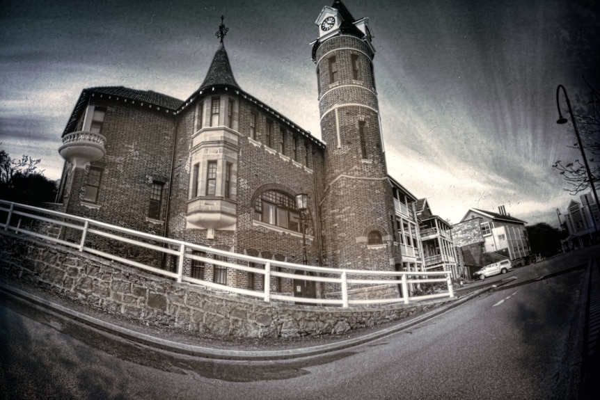 A fisheye photo of an old, stone church with a clock tower 