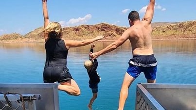 A woman, child and man jumping into a lake. 