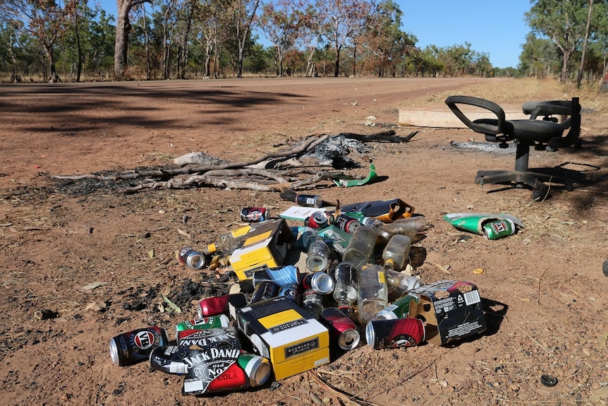 Piles of cask wine boxes and beer cans near a dirt road at Barunga