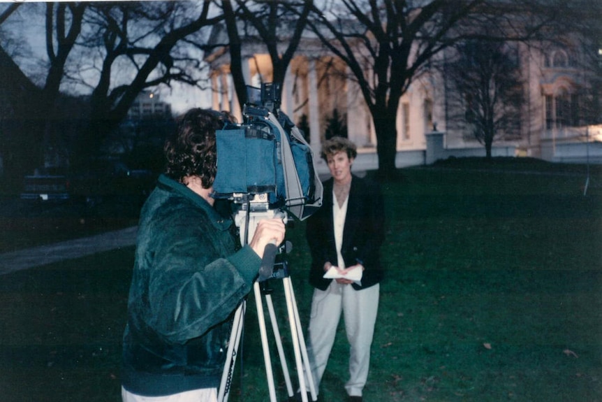 Ewart standing outside White House being filmed by camera operated by cameraman.