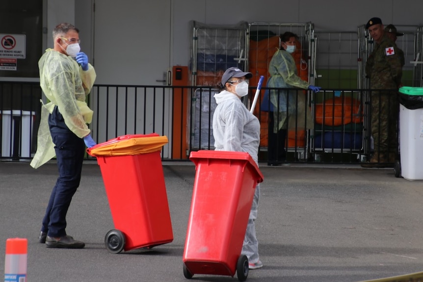 Cleaners carry bins at the North West Regional Hospital in Burnie during a coronavirus outbreak