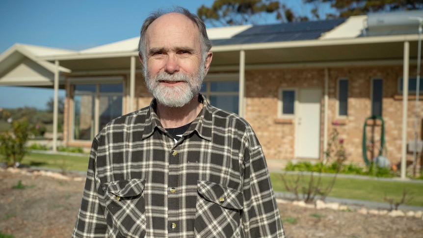 Rolf Wittwer stands outside his house, which has solar panels on the roof.