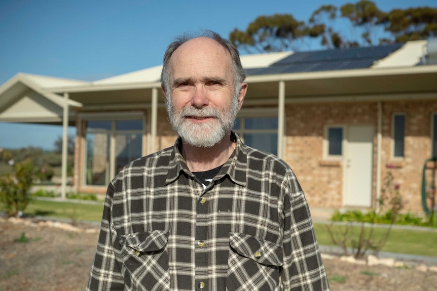 Rolf Wittwer stands outside his house, which has solar panels on the roof.