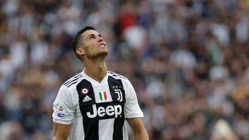 A man wearing a black and white striped shirt looks up at the sky.