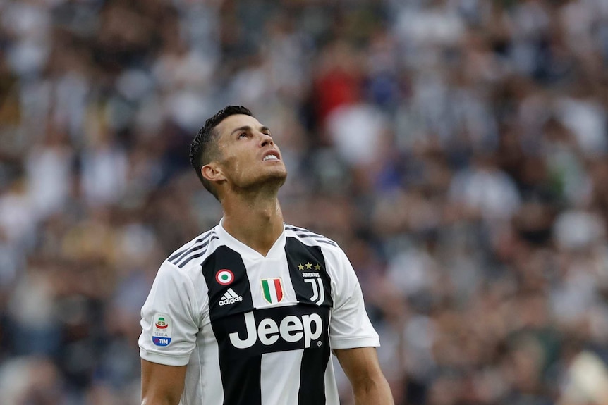 A man wearing a black and white striped shirt looks up at the sky.