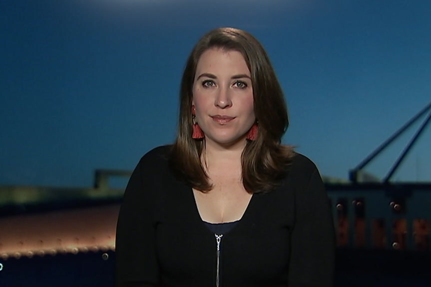 Annika Smethurst sits in a TV studio with parliament house behind her