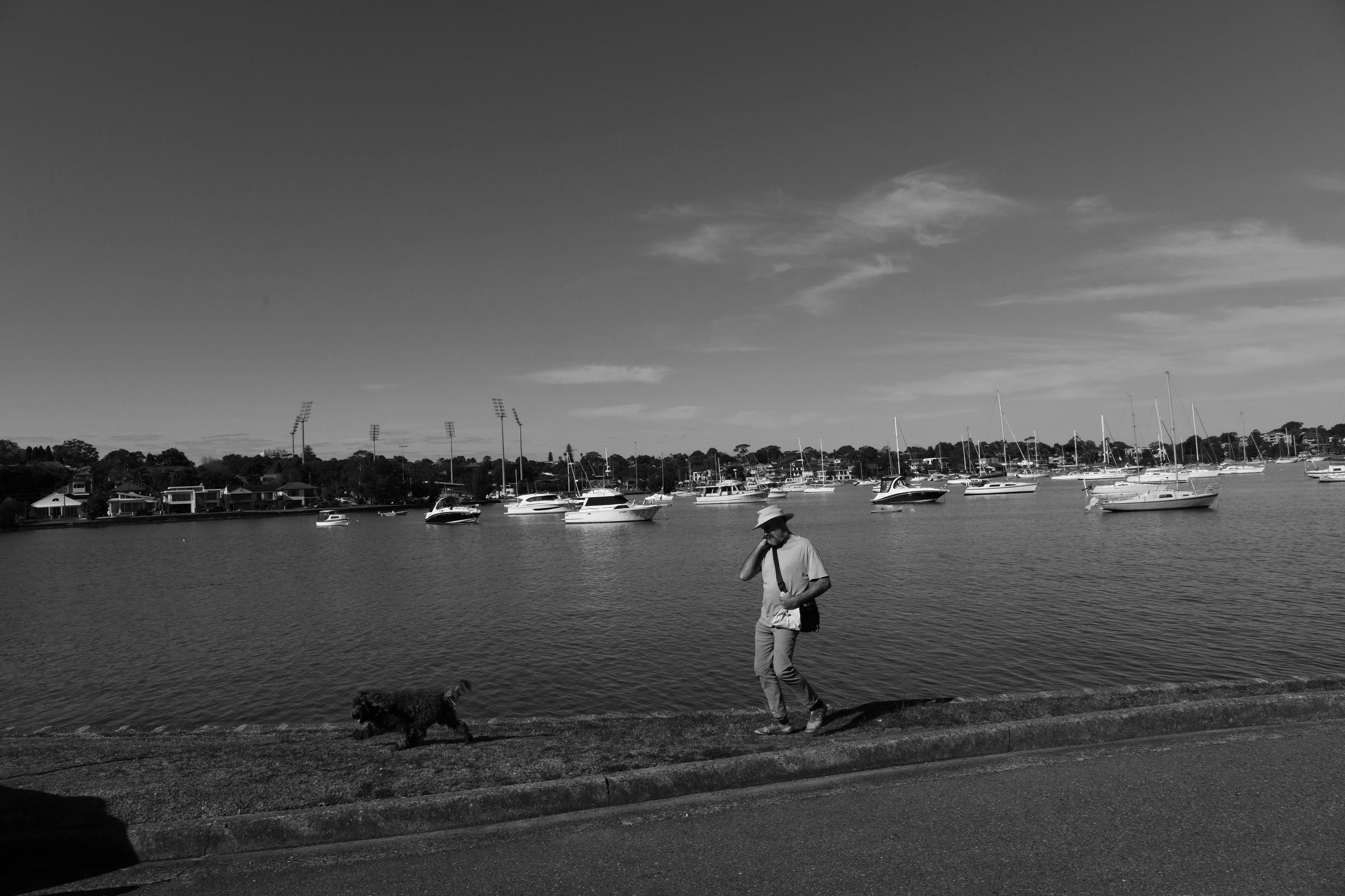 A man holds his bag as he walks along the water