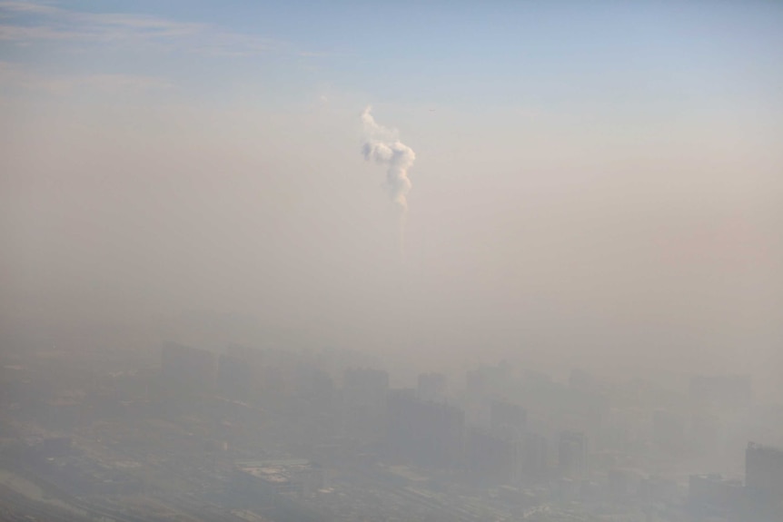 A chimney of a power plant is pictured among smog as a red alert for air pollution is issued in Beijing