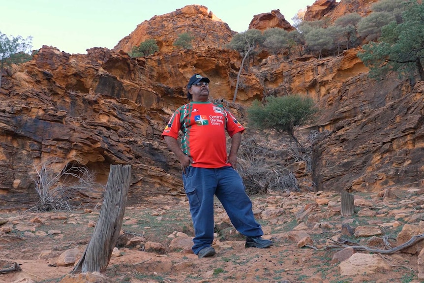 Man standing amid rocky cliffs.