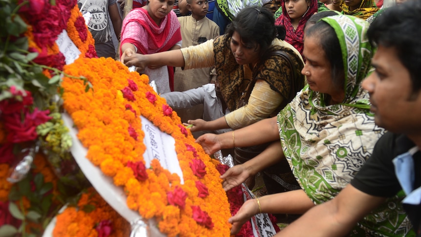 Bangladeshi people lay floral wreaths in memory of the victims of Rana Plaza