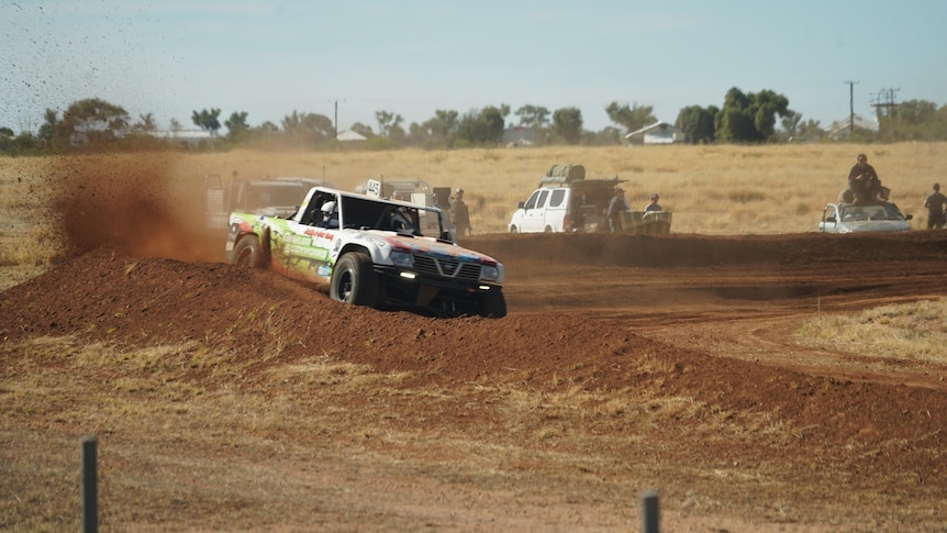 truck kicking up dirt as it takes on a tight bend on a race track