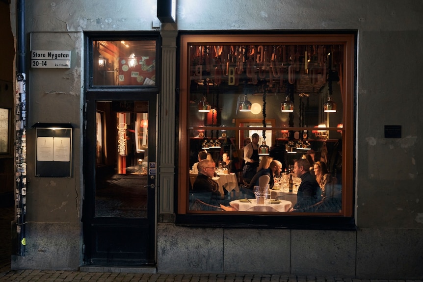 A view through a window of people sitting at a restaurant in Sweden during the coronavirus outbreak.