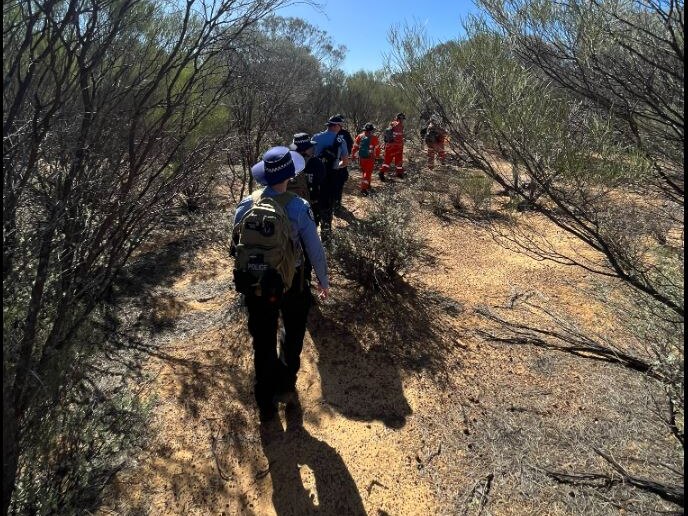 Image of SES and Police searchers conducting a land search in bushland near sandstone.