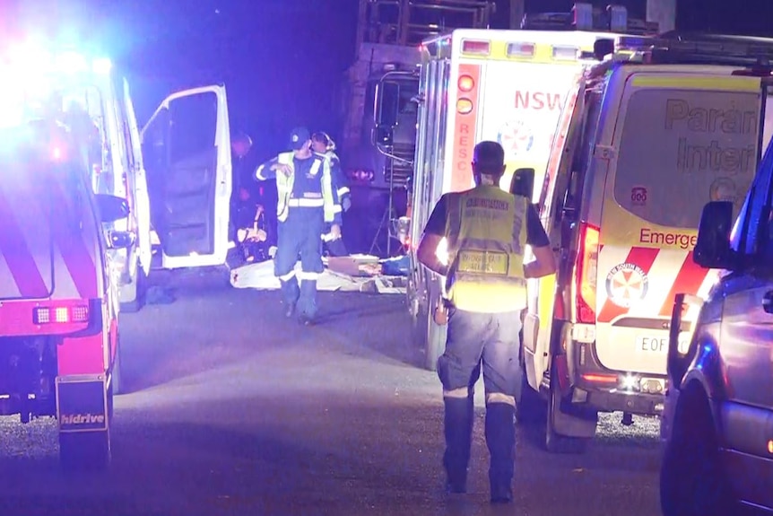 Ambulances with flashing lights at night time at the scene of a crash.