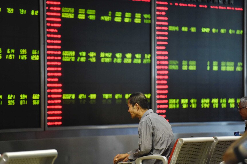 Investors look at screens showing stock market movements