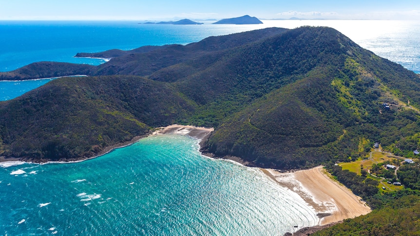 a beautiful green island with sandy beaches on a sunny day, photo taken from the air