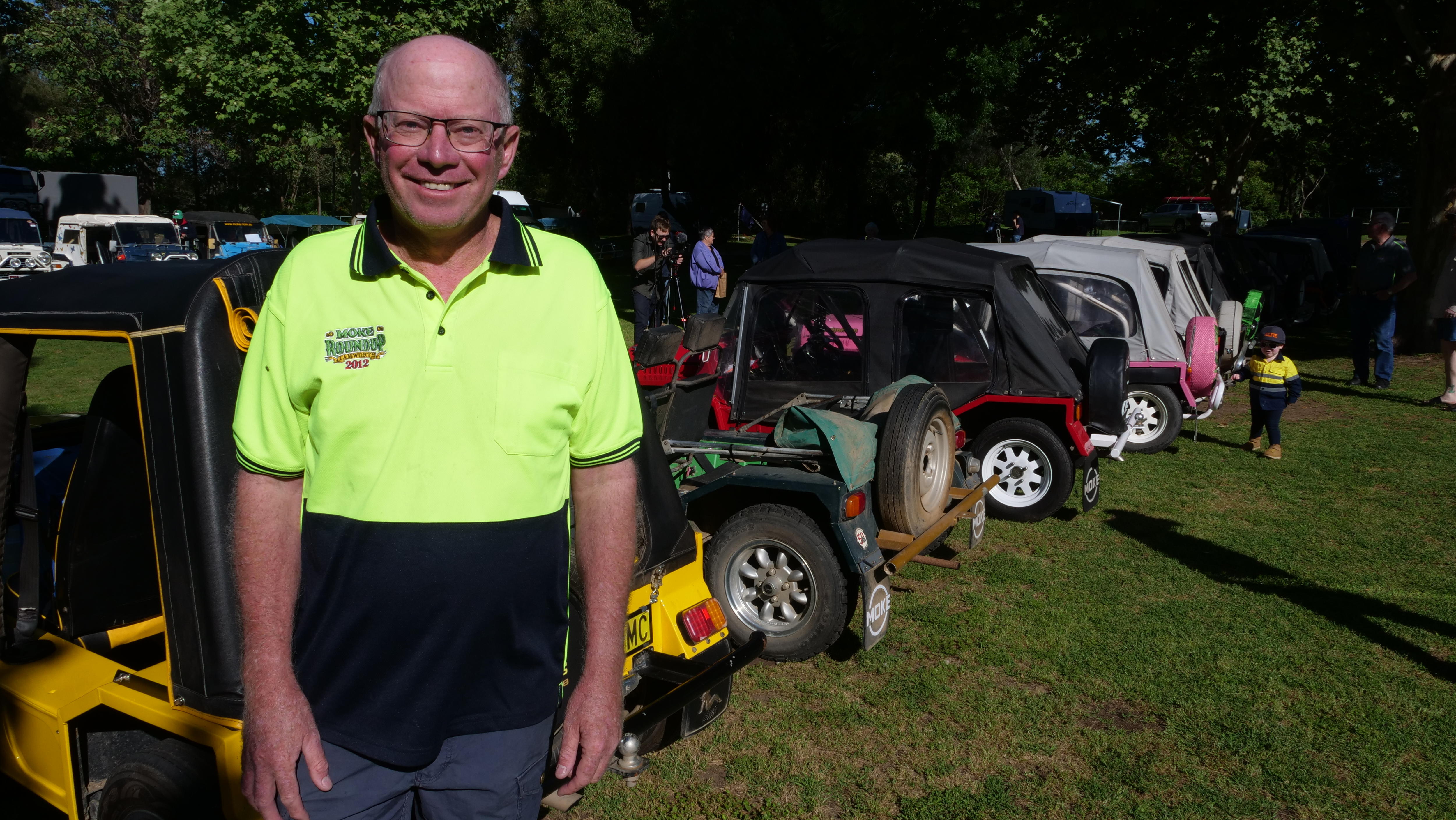 A man in a high-vis shirt stands in front of a row of Mini Mokes.
