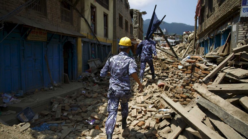 Nepalese police personnel run to rescue earthquake victim